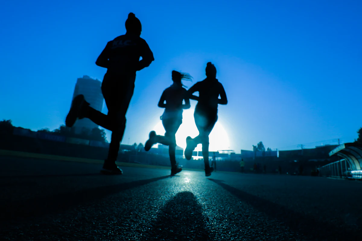 Tre persone che corrono in controluce all’alba